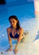 A woman in a blue bikini sitting in a pool.