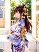 A woman in a blue and white kimono standing on a porch.