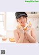 A woman in a hat and gloves holding a banana.