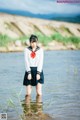 A woman in a school uniform standing in the water.