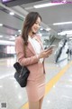 A woman in a pink suit is looking at her phone.