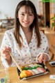 A woman sitting at a table with a tray of sushi.