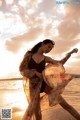 A woman in a bathing suit is dancing on the beach.