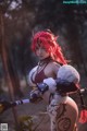 A woman with red hair holding a sword in a forest.